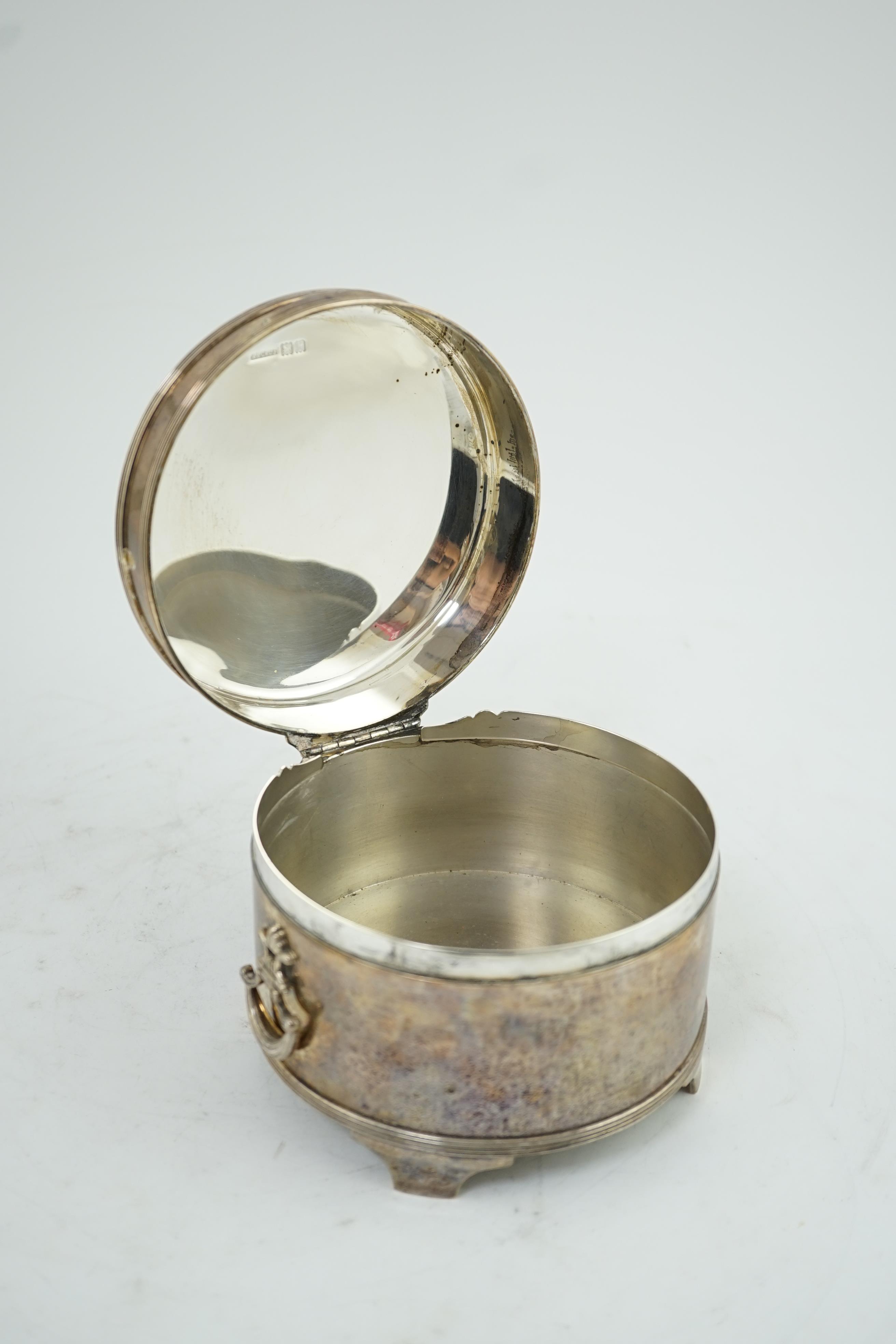 A George V silver circular two handed biscuit box, with hinged cover, by Asprey & Co Ltd